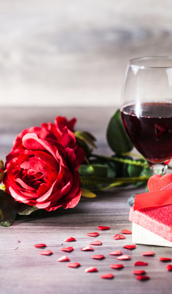 Розы, подарок и два бокала вина на столе