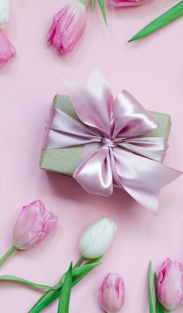 Тюльпаны на розовом фоне с подарком и десертом макарон 