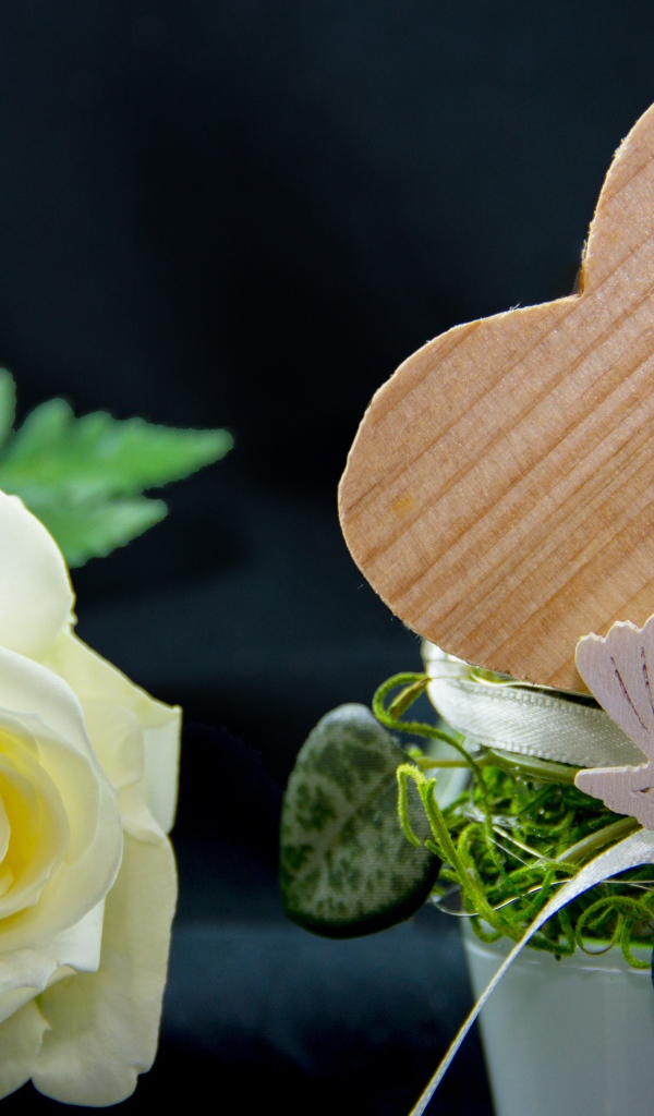 Деревянное сердце и белая роза на столе 