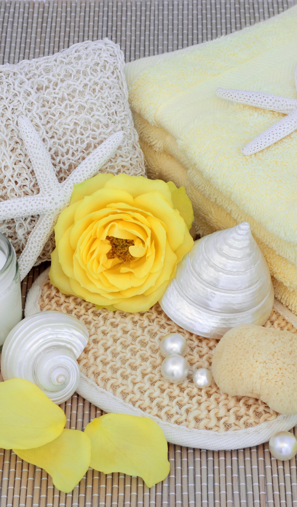 Желтые розы на столе с полотенцем, ракушками и мылом