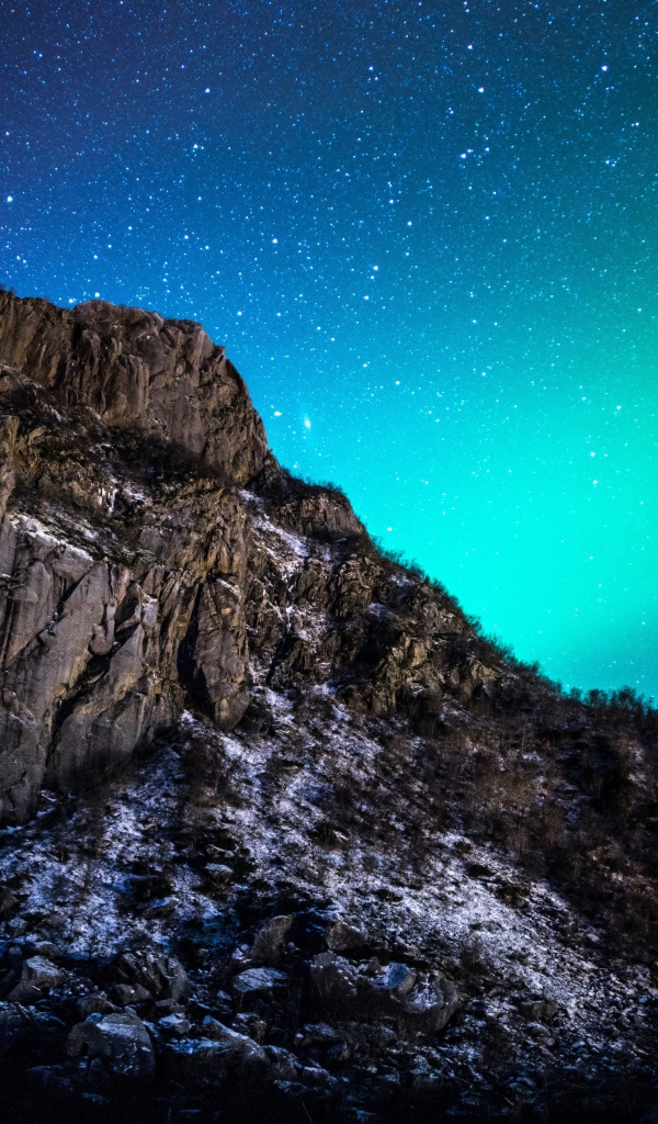 Красивое зеленое полярное сияние в звездном небе над горой 