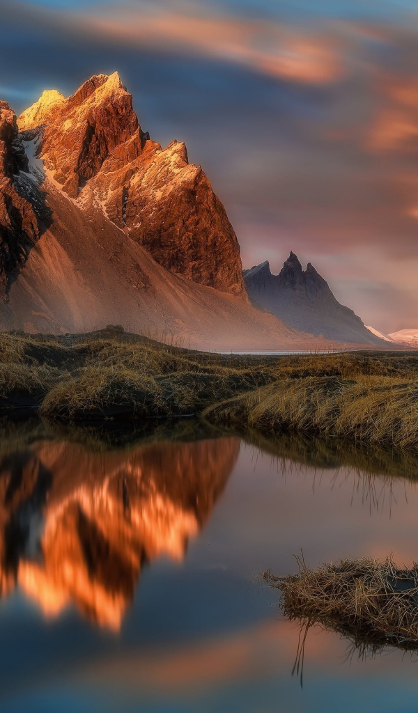 Красивое розовое небо над заснеженными горами у залива 