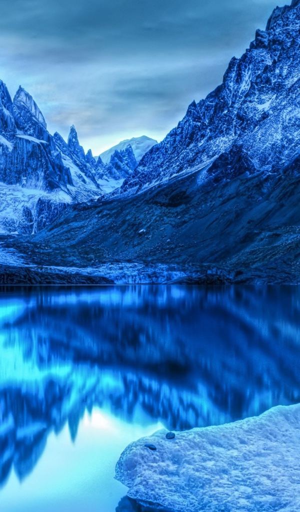 Голубой холодный закат на заснеженными горами у озера 