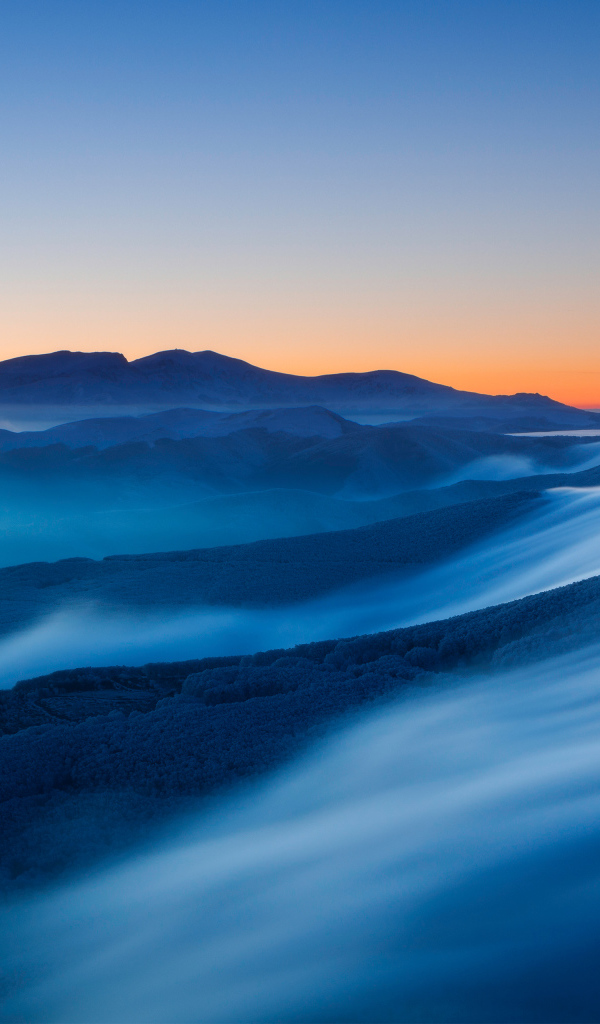 Туман покрывает высокие горы на рассвете 
