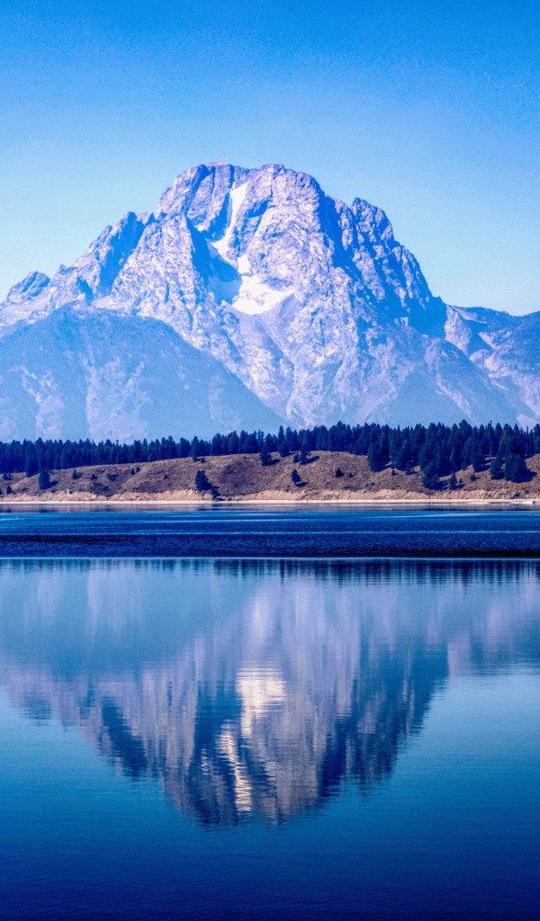 Высокие горы отражаются в озере под голубым небом