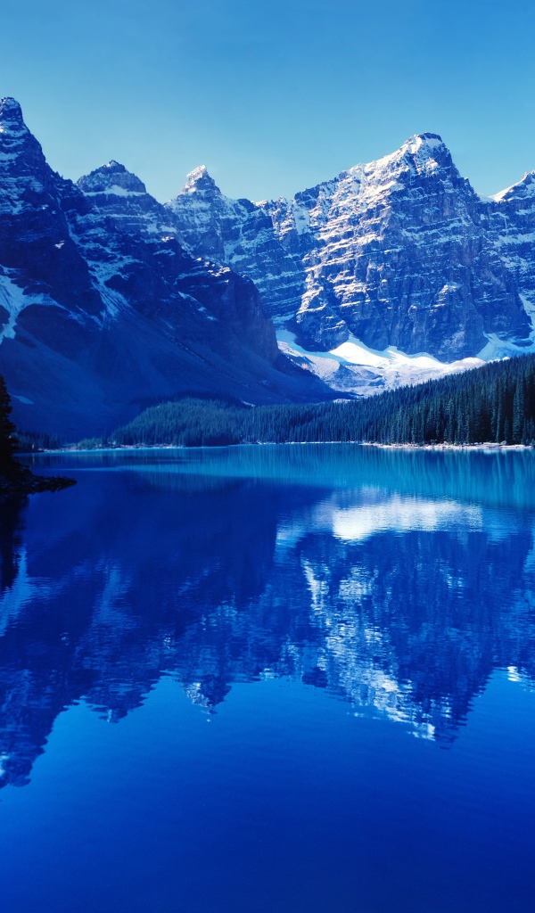 Высокие заснеженные горы отражаются в воде озера 