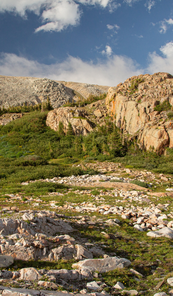 Высокие каменные горы под  голубым небом с белыми облаками