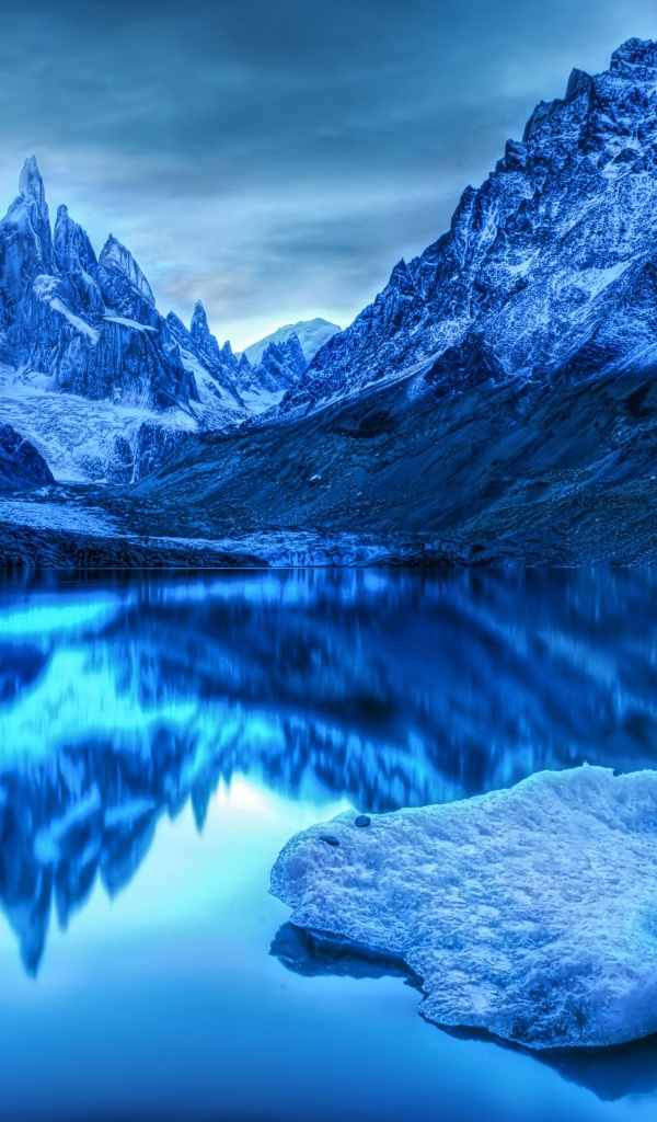 Заснеженные горы отражаются в воде в сумерках