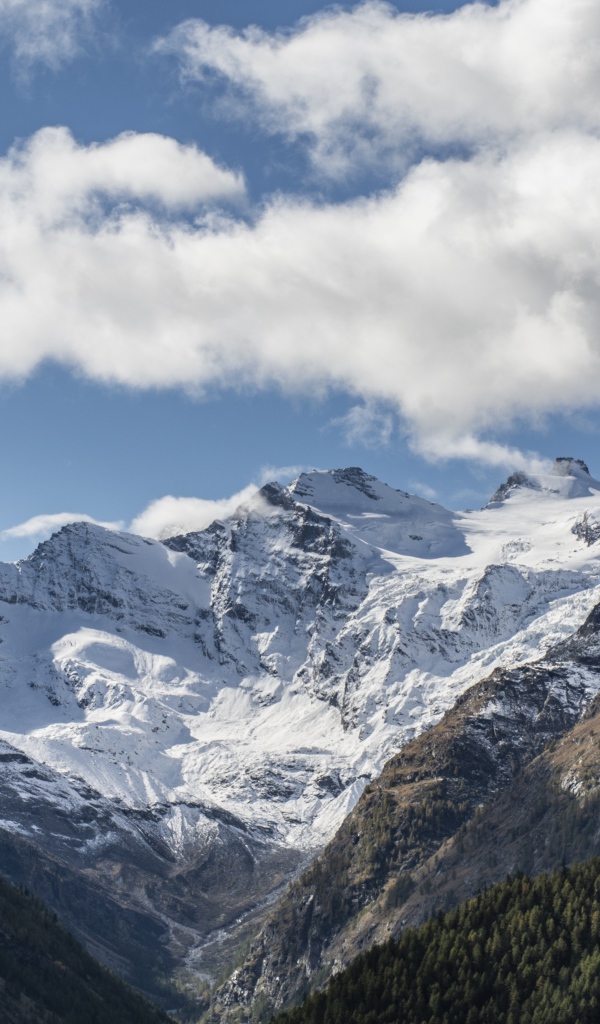 Заснеженные горы под голубым небом с белыми облаками