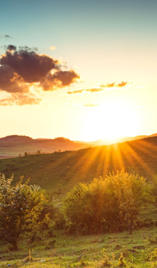 Яркое летнее солнце встает из-за гор 