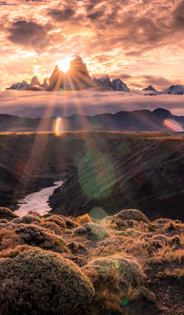 Лучи яркого солнца пробиваются сквозь вершину горы на рассвете 