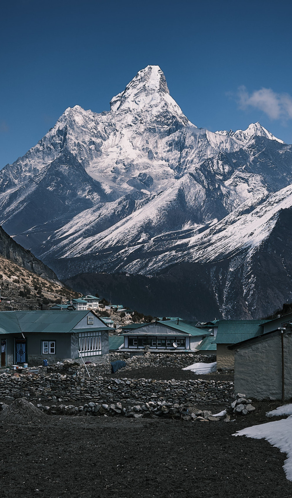 Поселок на фоне заснеженных гор под голубым небом 