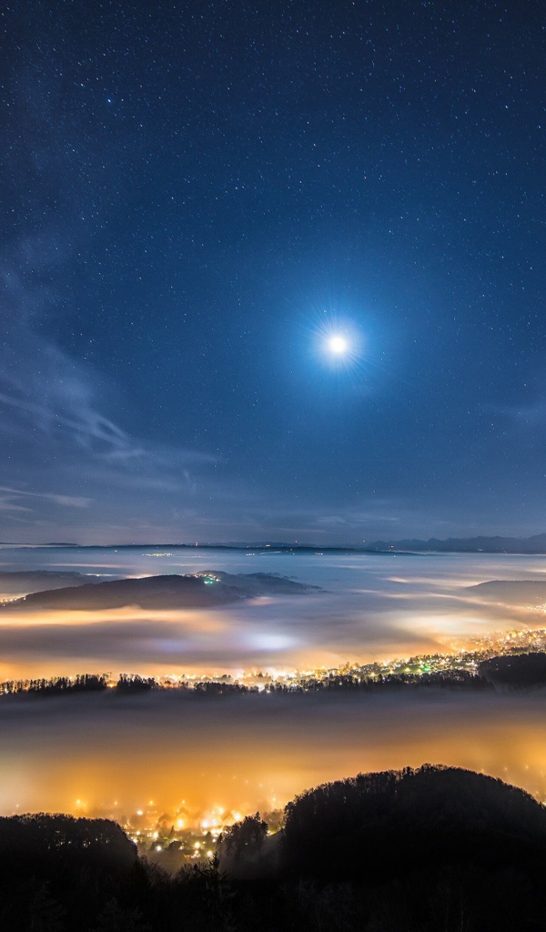Вид с горы на покрытый туманом ночной город 