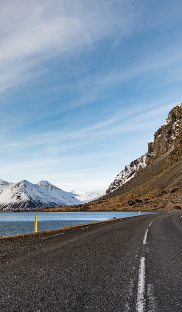 Асфальтовая дорога ведет в горы под голубым небом