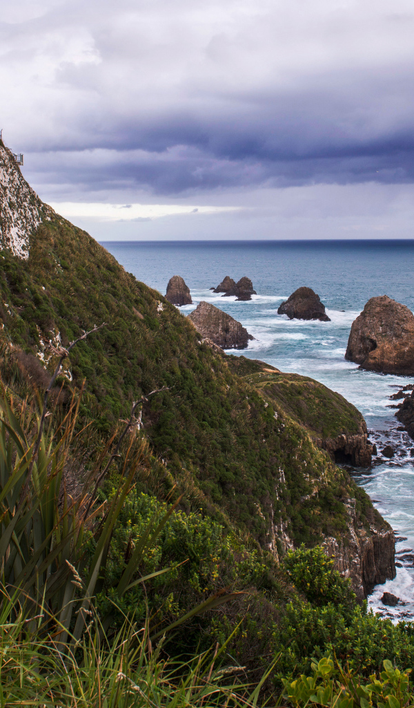 Маяк на вершине утеса у моря под грозовым небом