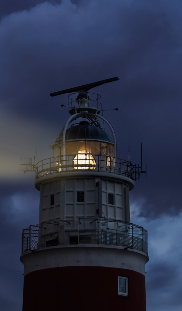 Грозовое небо над включенным маяком ночью