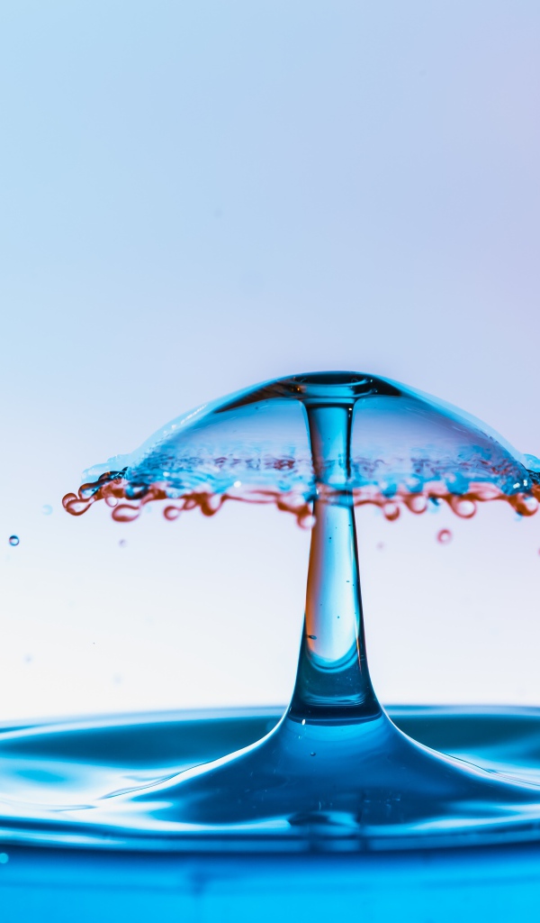 Зонтик из воды в стакане на сером фоне