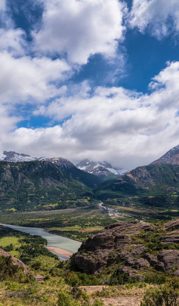 Белые облака в голубом небе над покрытыми зеленью горами