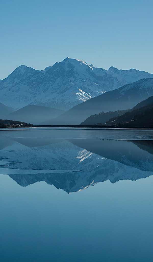 Холодное озеро покрывается льдом у гор