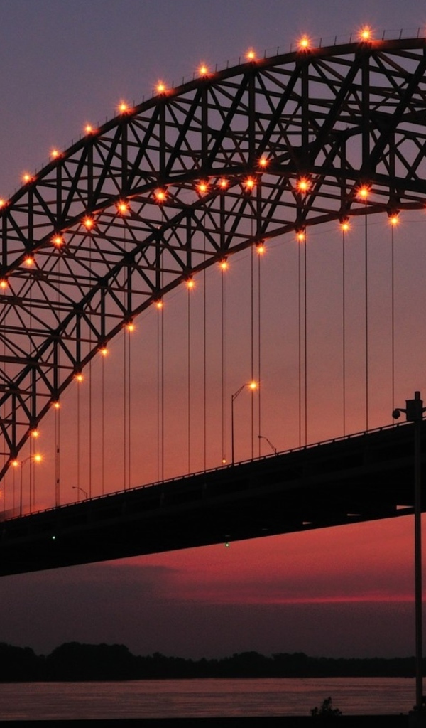 Арки на железном мосту с фонарями ночью через реку 