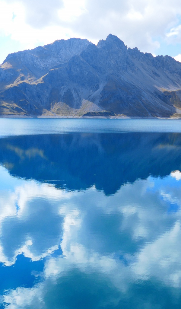 Большое голубое озеро в горах под голубым небом 