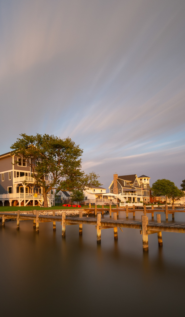 Мост у дома над тихой рекой под красивым небом