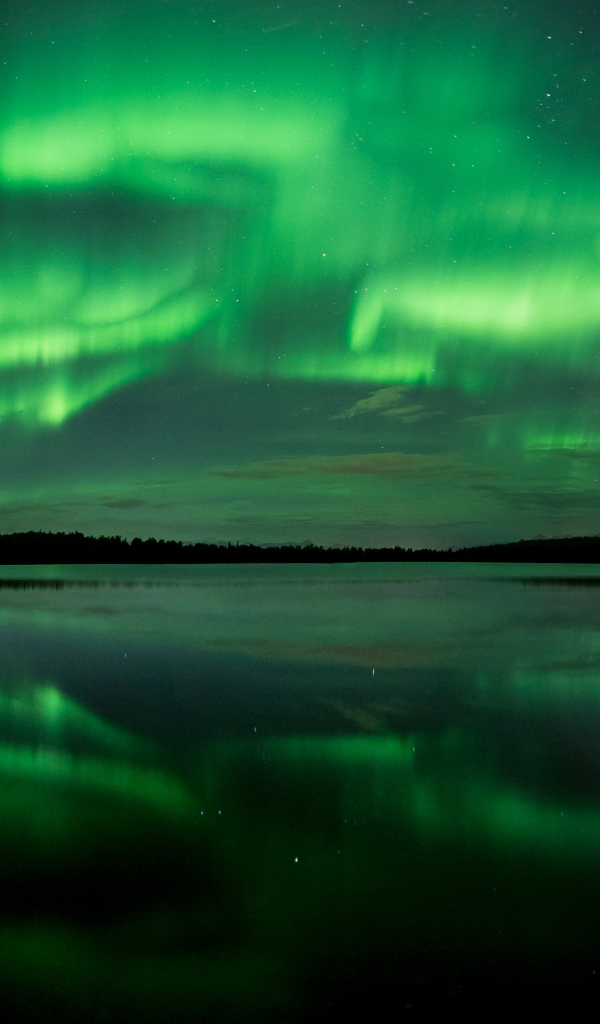 Зеленое северное сияние отражается в воде озера ночью 