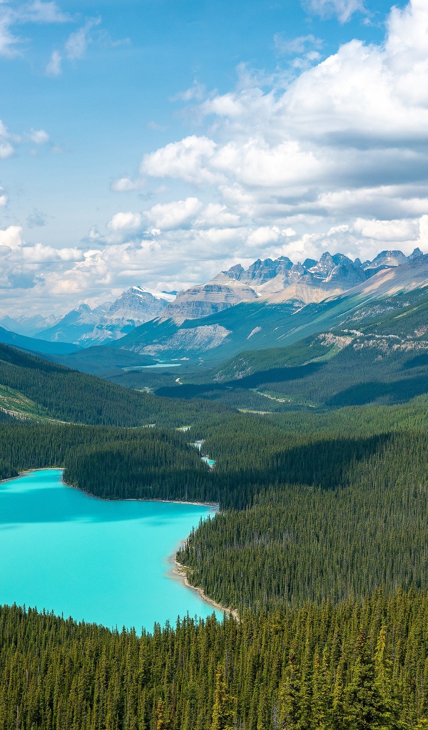 Вид на красивое голубое озеро и горную долину под солнечным небом с белыми облаками