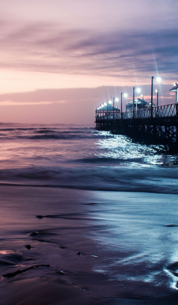 Вид на мост в океане с включенными фонарями ночью