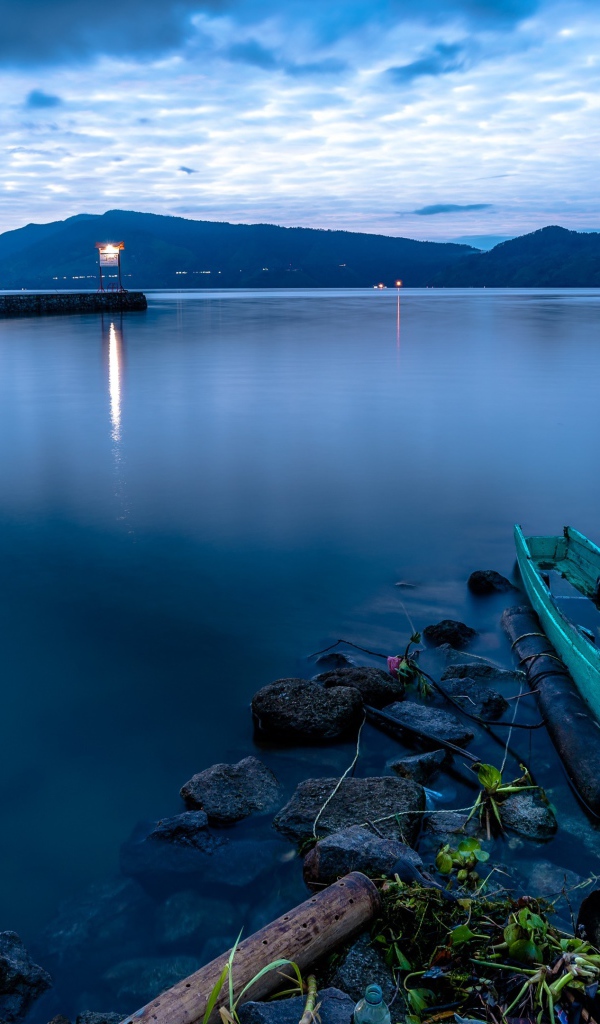 Деревянная лодка на берегу тихого озера в сумерках 