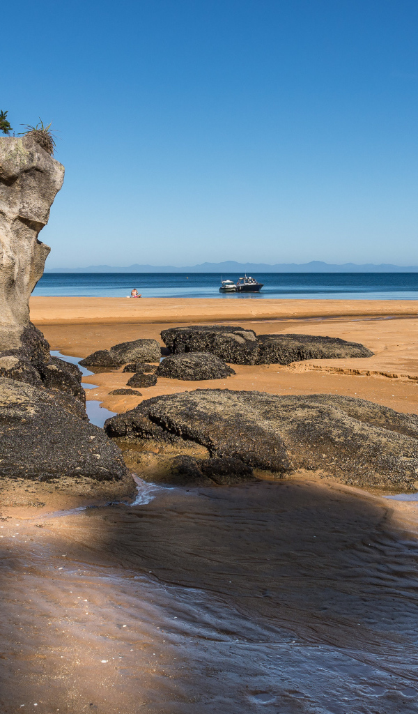 Большие камни на берегу на мокром песке у моря летом 