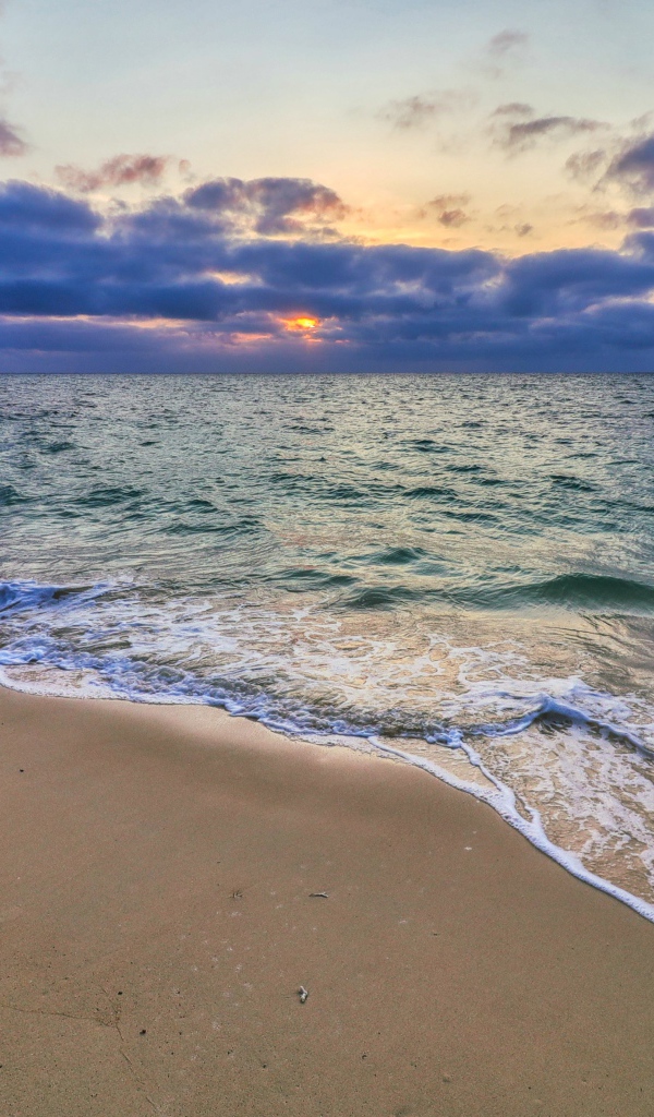 Blue sea water on the sand at sunset
