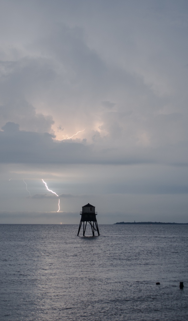 Старая башня в море на фоне грозы 