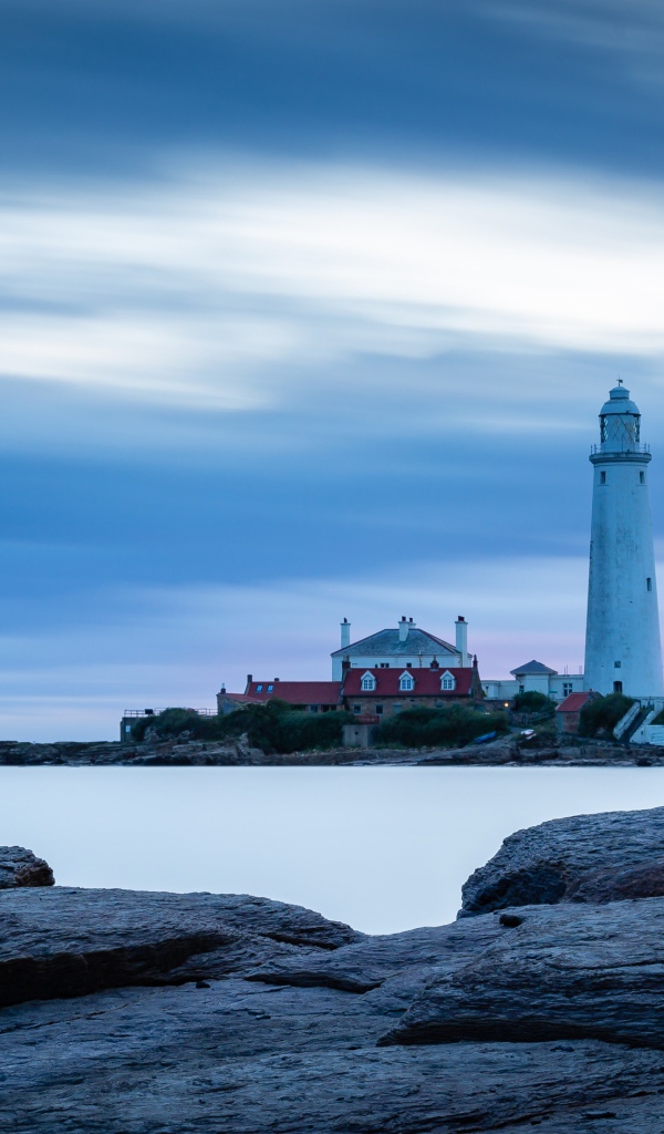 Вид с каменного берега на маяк в море 