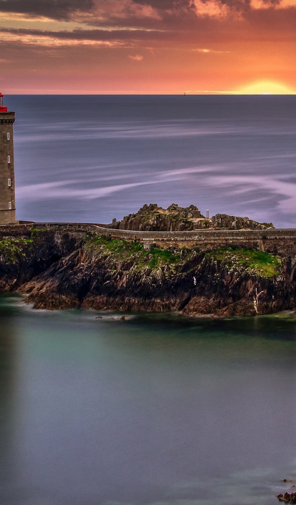 Вид на спокойное море и маяк на закате солнца 