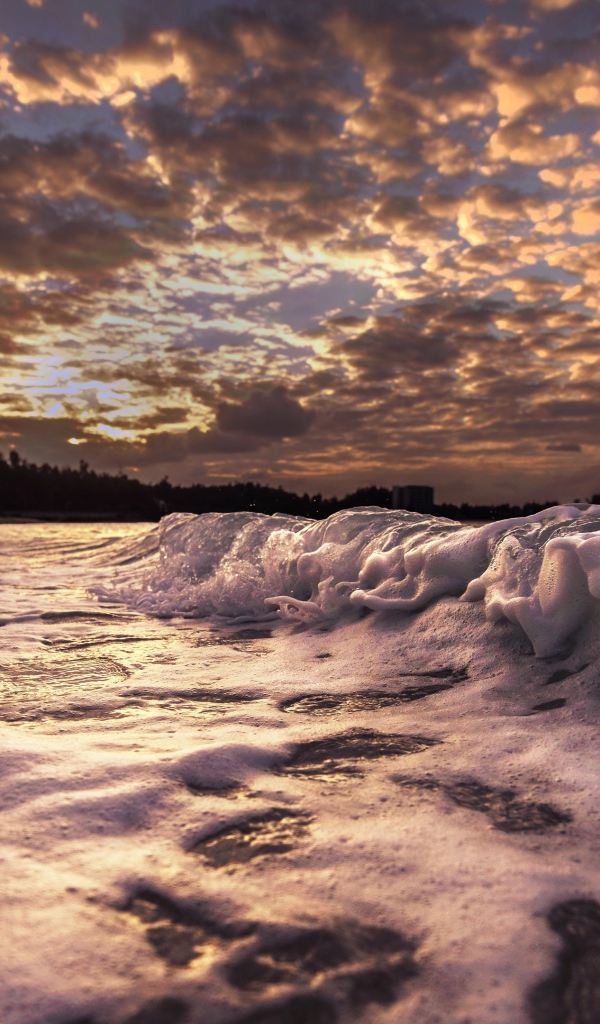 Белые волны на песке на рассвете 
