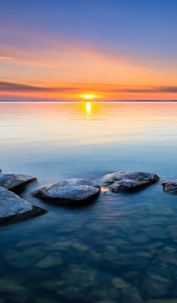 Большие камни в воде на закате яркого летнего солнца 