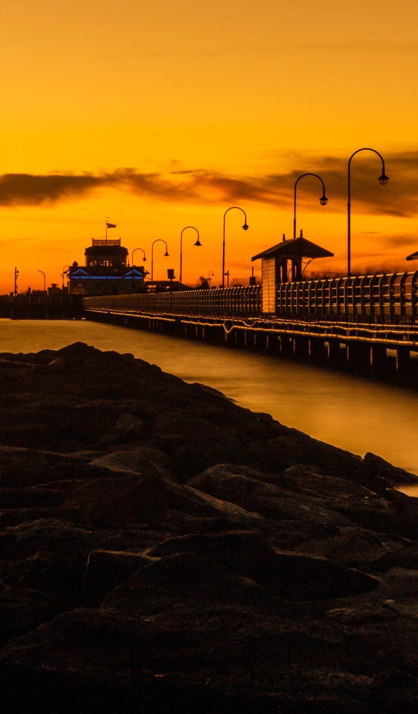 Длинный мост на морском побережье на закате 