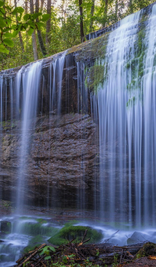 Холодная вода водопада стекает по мокрой скале