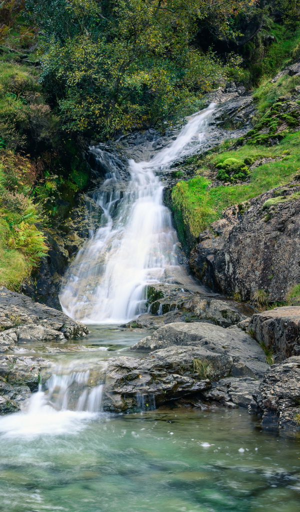 Горный ручей стекает по камням в реку 