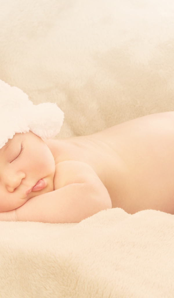 Грудной ребенок с белой шапке спит на кровати