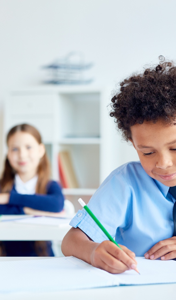 Маленький мальчик сидит за партой в классе