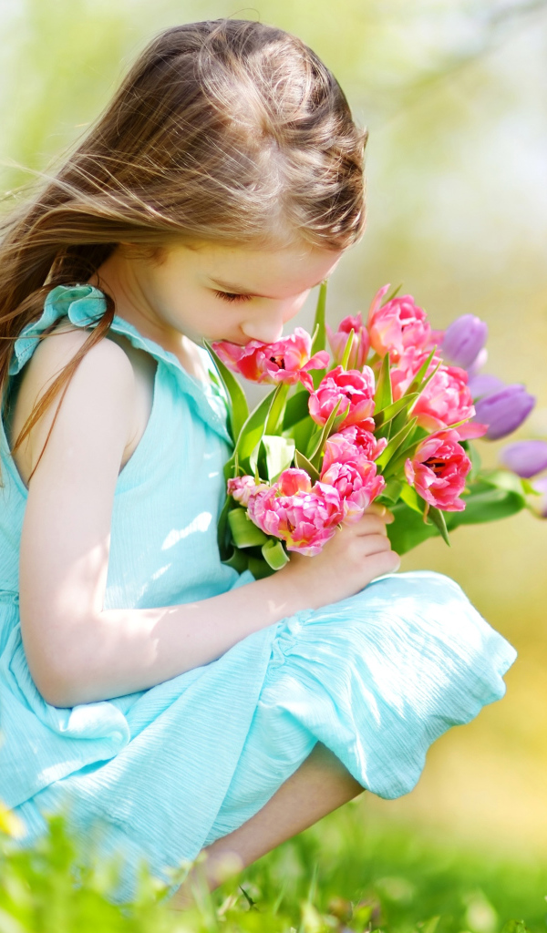 Красивая девочка в голубом платье с букетом тюльпанов