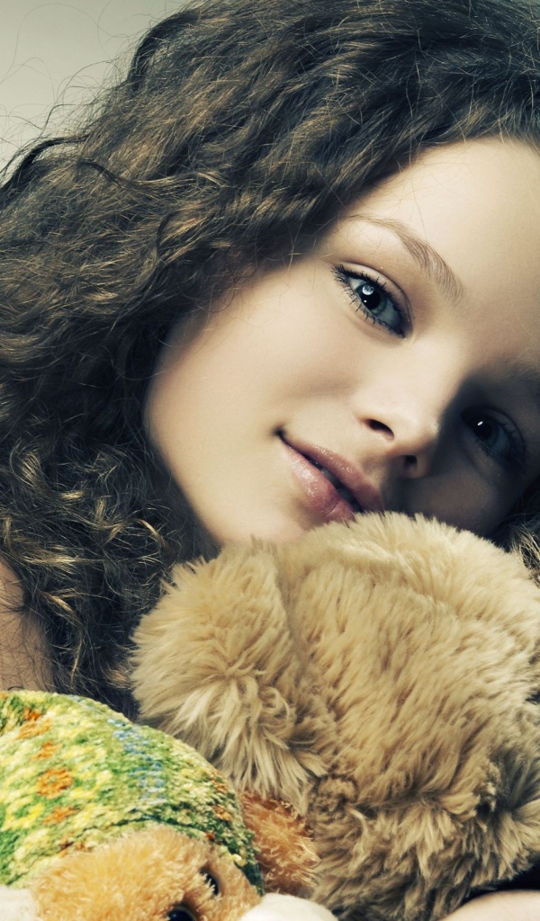 Красивая девочка с длинными волосами с медведем в руках 