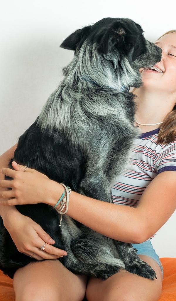 Веселая девочка с собакой в руках 