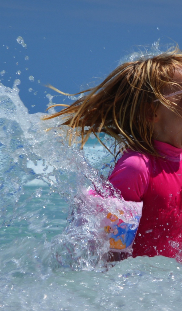 Веселая маленькая девочка купается в море летом