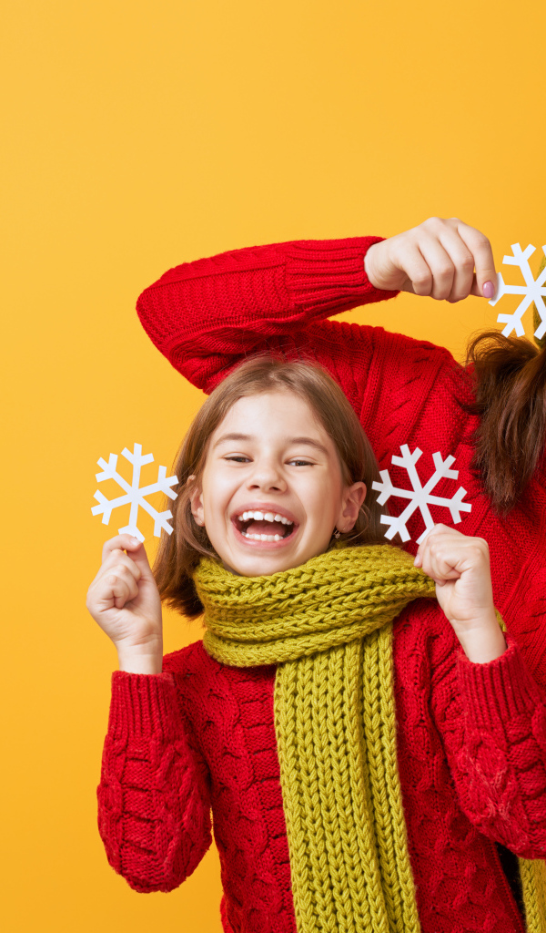 Веселые мама и дочка в красных свитерах на оранжевом фоне