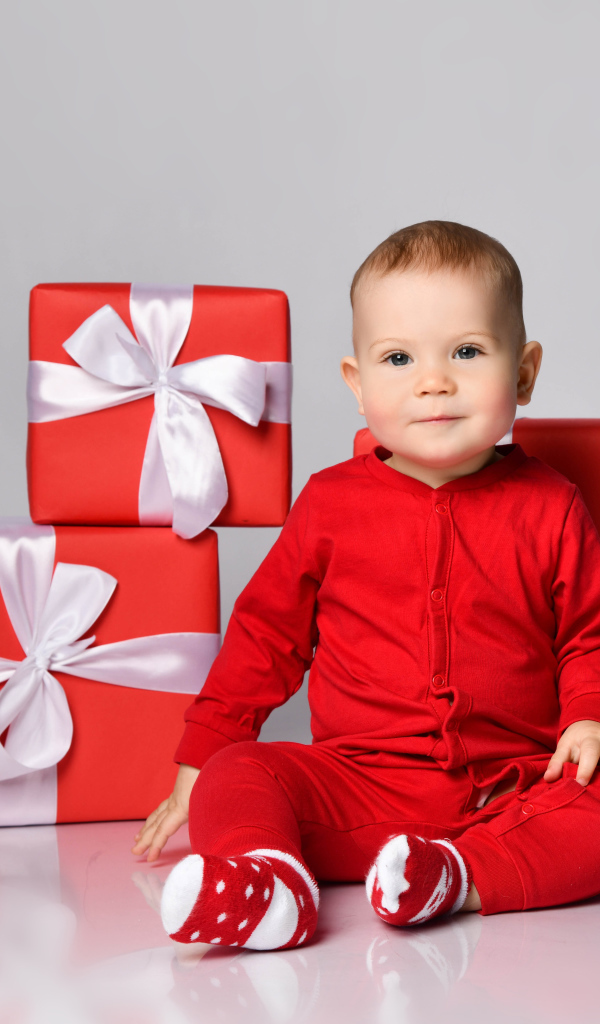 Милый малыш в красном костюме с подарками на новый год 
