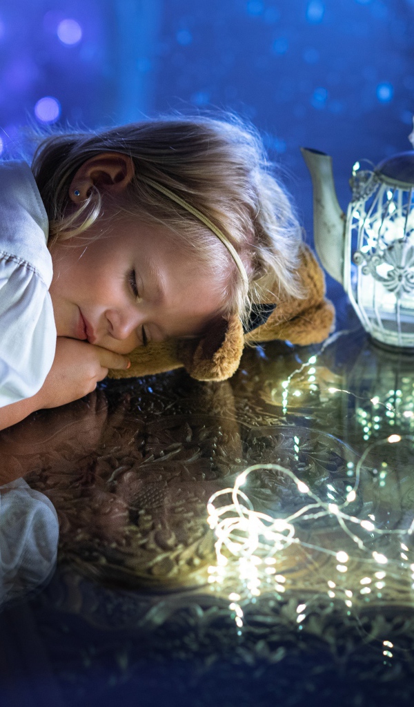 Милая маленькая девочка в белом платье спит на столе