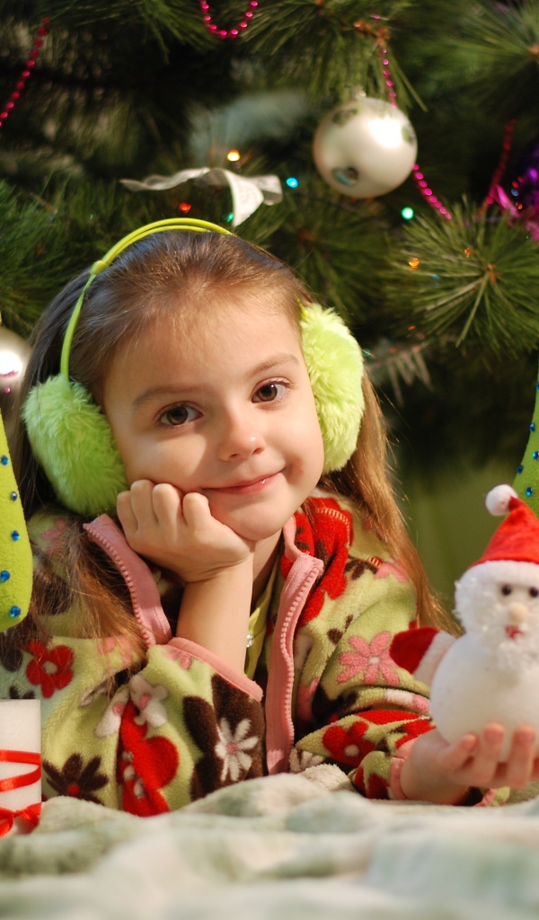 Милая маленькая девочка с игрушками под елкой 
